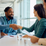 Happy black financial advisor handshaking with his clients during a meeting in the office.