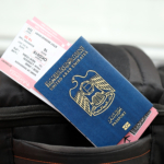 Blue United Arab Emirates passport with airline tickets on touristic backpack