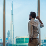 Businessman gazing through window with city view, Dubai, United Arab Emirates