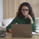 Young pleasant Italian woman freelancer working on laptop computer remotely at home